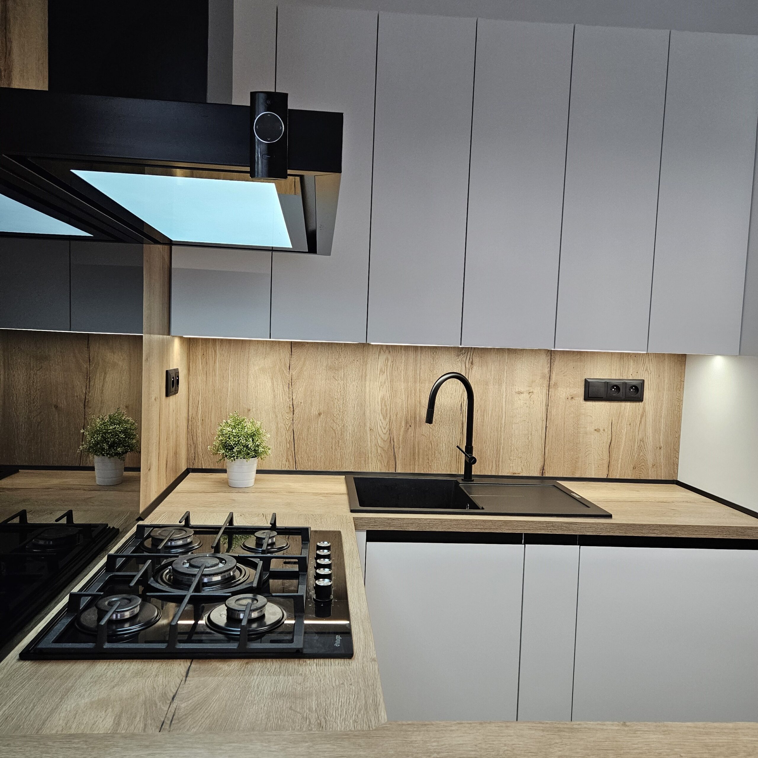 Elegantní kuchyň na míru pro klientku na Smržovce Místo, kde design neustupuje pohodlí. Tato kuchyň spojuje precizní řemeslo s moderními prvky, čímž vzniká harmonický prostor, který je stejně krásný jako funkční. Korpus v odstínu Arktická bílá doplňuje pracovní deska a zadní obklad v dekoru Dub Halifax přírodní, které dodávají interiéru útulnost a přírodní charakter. Spodní skříňky jsou osazeny zápustnými úchytkami Grande v elegantní černé matné, horní části pak využívají subtilní profil S068 v identickém odstínu pro zachování čistých linií. Samozřejmostí je kvalitní kování rakouské firmy Blum, které zajišťuje dlouhou životnost a pohodlné každodenní používání. Kuchyň je dále vybavena luxusními spotřebiči De Dietrich.